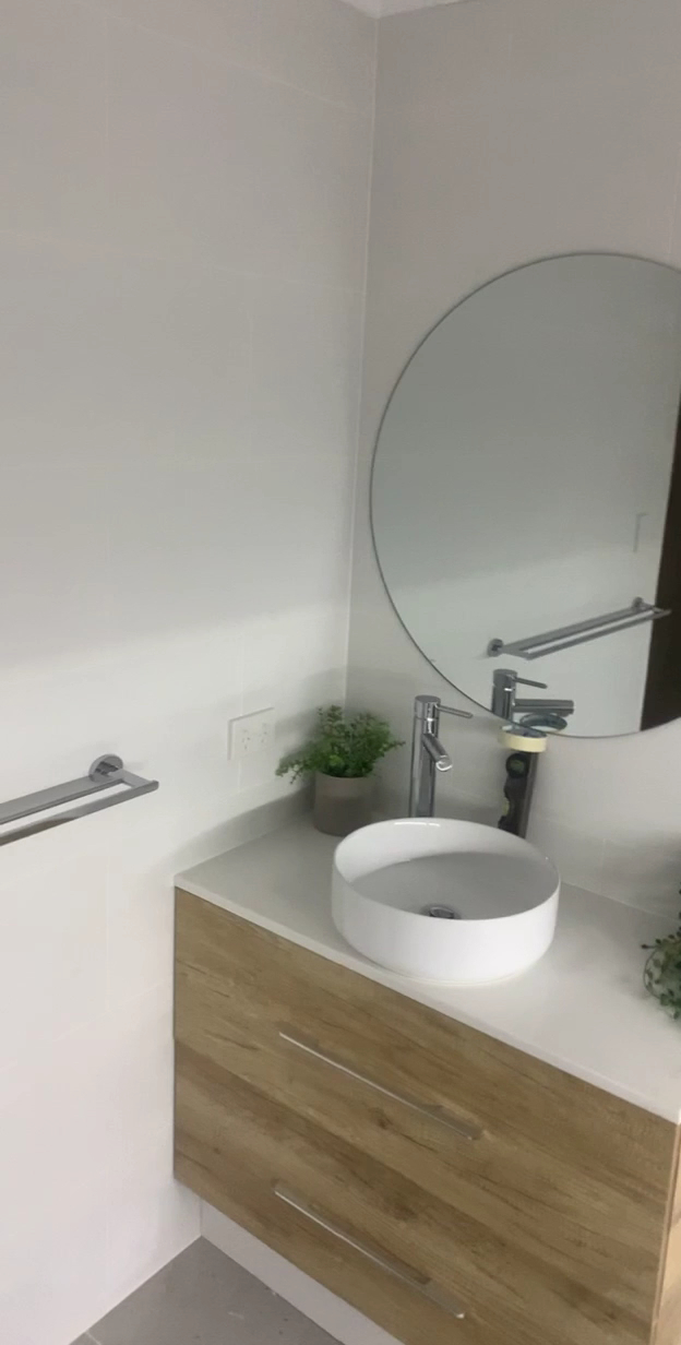 White vessel basin on a timber-look floating vanity with a round mirror