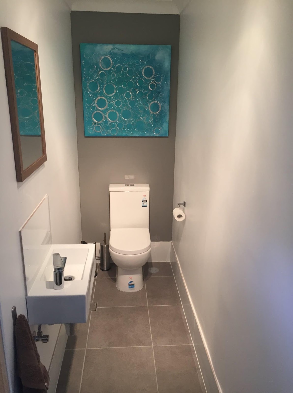 Powder room with a wall-hung basin, toilet and a grey feature wall