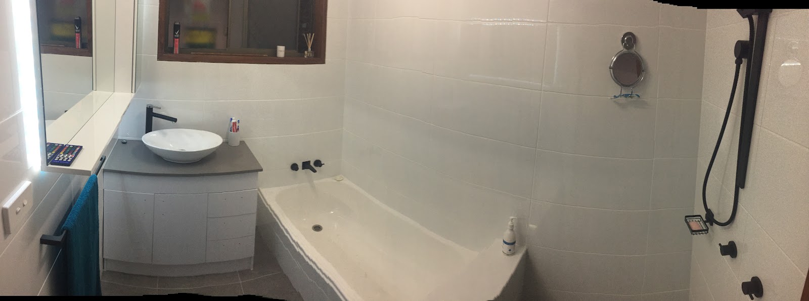 Bathroom with a bath, vessel basin on a white vanity and matte black tapware